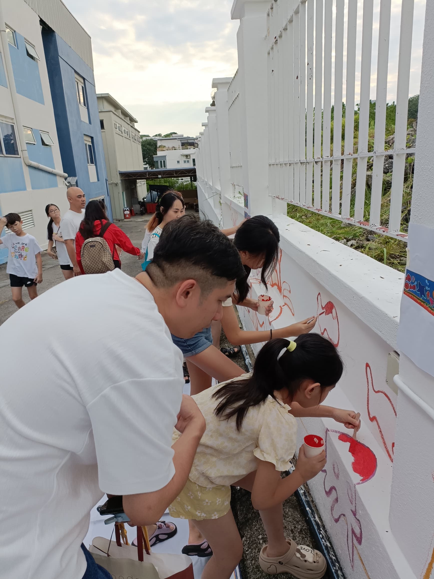 An adult volunteer guiding a young girl as she paints a section of the mural during the JKM Petaling volunteer morning.